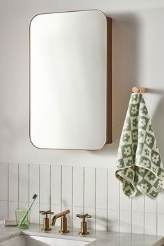 a bathroom sink with a mirror above it and two towels hanging on the wall next to it