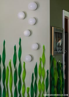 the wall is decorated with green plants and white vases on it's sides