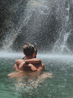 a boy is sitting in the water and splashing with his hands over his head