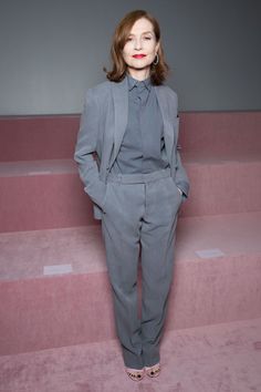 a woman standing in front of some steps wearing a suit and heels with her hands on her hips