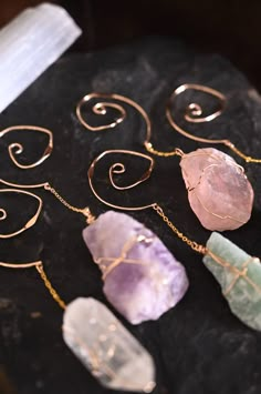 four different types of crystals on a black stone slab with gold chains and earring wires