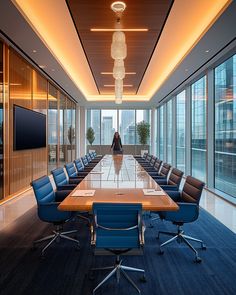 an empty conference room with blue chairs and a large wooden table in front of windows