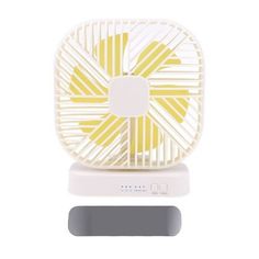 a yellow and white fan sitting on top of a table next to a gray object