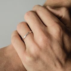 a man's hand with a ring on his left wrist, wearing a white gold band