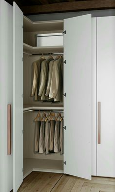 an open closet with clothes on hangers and pants hanging from the doors, in front of a wooden floor