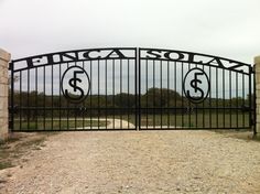 an iron gate with the words finca sora and dollar signs on it in front of a stone wall