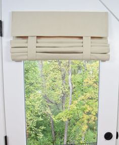 an open door with a window in front of it and trees outside the window,