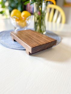 a wooden cutting board sitting on top of a table next to a vase filled with flowers