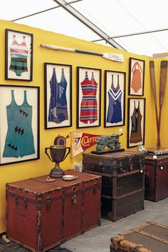 there are many pieces of luggage on display in this room with yellow walls and pictures