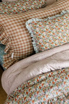 a bed with many pillows on top of it and a checkered pillow case in the middle