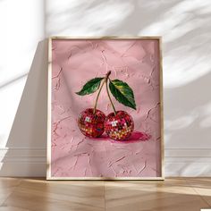 two cherries on a pink background in a wooden frame, with the shadow of a wall behind them