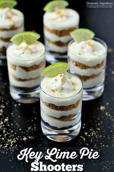 small desserts with lime slices and whipped cream on top are arranged in individual glasses