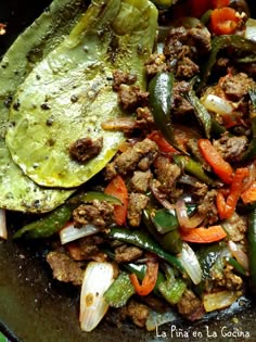 a skillet filled with meat, peppers and other vegetables on top of a table