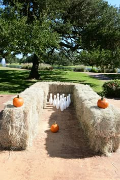 bowling pins and pumpkins are placed on hay bales