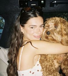 a woman holding a dog in her arms while sitting in the back seat of a car