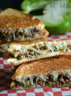 two grilled sandwiches sitting on top of a red and white checkered table cloth