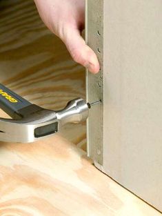 a person using a pair of pliers to attach a piece of wood on the floor