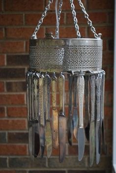 a chandelier hanging from a brick wall with spoons and knives in it