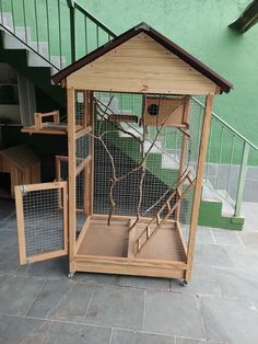 a small wooden bird cage sitting on top of a stone floor next to a stair case