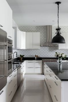 a large kitchen with white cabinets and black counter tops, along with stainless steel appliances