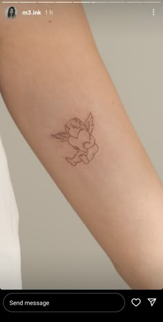 a small tattoo on the arm of a woman's left arm, with an angel holding