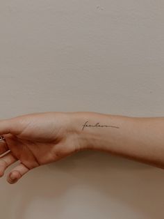 a woman's left arm with a small tattoo on her left wrist and the word love written in cursive writing