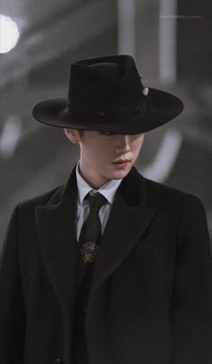 a woman in a black suit and hat is looking down at the camera while standing