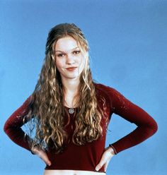 a young woman posing for a photo with her hands on her hips, wearing a red shirt and white skirt