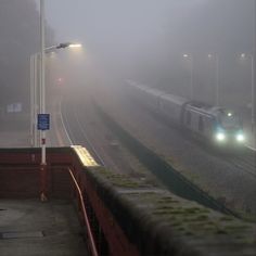 a train traveling down tracks in the fog