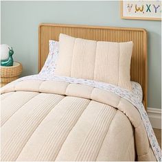 a bed with two pillows on top of it and a basket next to the headboard