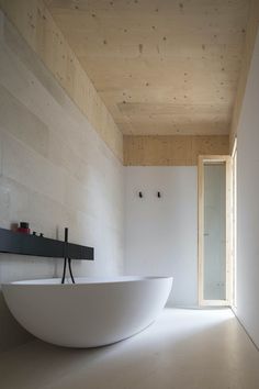 a large white bath tub sitting under a wooden ceiling