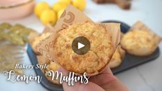 a person holding up a muffin in front of some lemons and other food