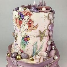 a three tiered cake decorated with mermaids and pearls