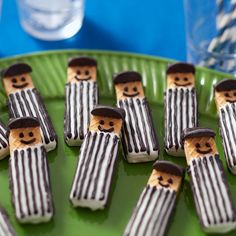 there are many small cookies made to look like men in hats and striped clothes on a green plate