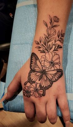 a woman's hand with a butterfly and flowers tattoo on it