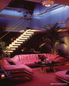 a living room filled with pink couches under a stair case next to a plant