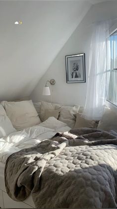 an unmade bed sitting in the corner of a room next to a large window