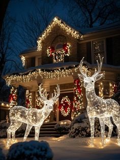 two reindeer statues in front of a house decorated with christmas lights