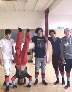 four young men standing in a room with one upside down