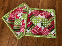 two quilted placemats sitting on top of a wooden table next to each other