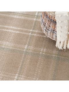 a basket with a blanket on top of it sitting next to a pillow and rug