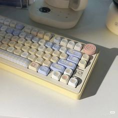 a computer keyboard sitting on top of a desk next to a cup and coffee mug