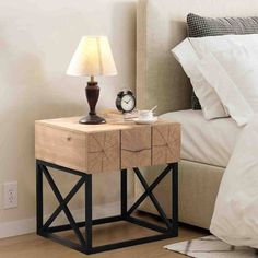 a nightstand table with a clock on it next to a lamp and bed in a bedroom