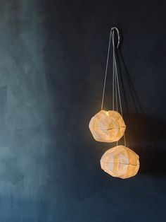 two lamps hanging from the ceiling in a room with dark walls and concrete flooring