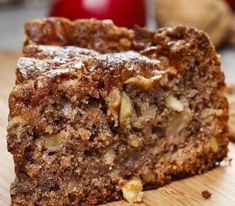 a piece of cake sitting on top of a wooden cutting board next to an apple