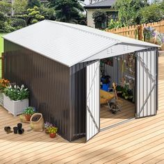 a small metal shed sitting on top of a wooden deck next to flowers and potted plants