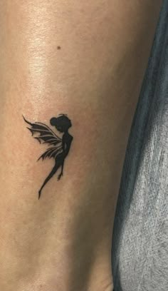 a small tattoo on the side of a woman's leg, with a black and white image of a fairy