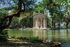 an old building sitting on top of a lake surrounded by trees