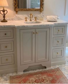 a bathroom vanity with marble top and gold accents