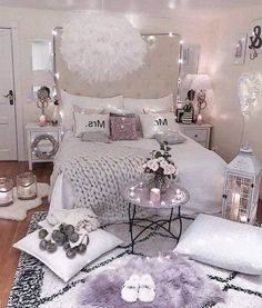 a bedroom decorated in white and pink with lots of lights